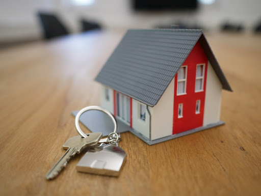 Miniature house and set of keys on a wooden table 